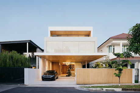 Modern two-story home with wooden accents, glass façade, and a parked vehicle in the driveway.