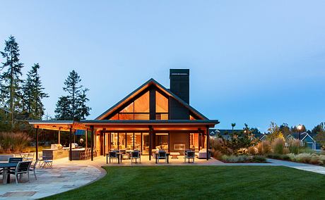 A contemporary lodge-style pavilion with a towering peak, expansive porch, and cozy seating areas.