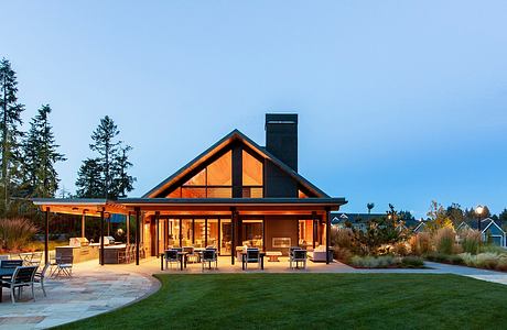 A contemporary lodge-style pavilion with a towering peak, expansive porch, and cozy seating areas.