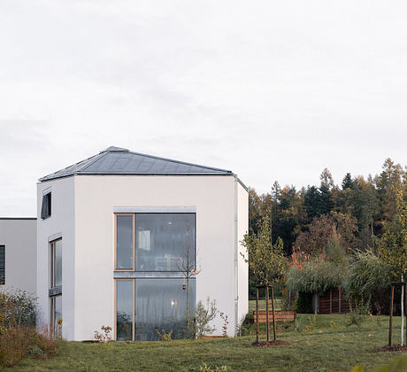 A modern, minimalist home with a striking roofline and large windows overlooking a lush garden.