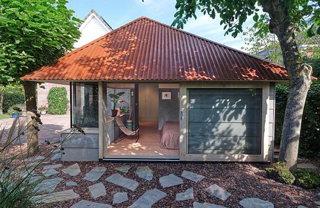 Rustic cabin-style home with a red-tiled roof, floor-to-ceiling windows, and a covered porch.