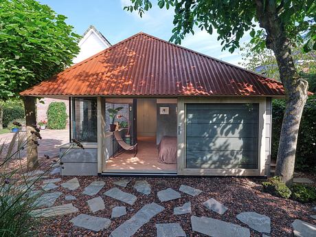 Rustic cabin-style home with a red-tiled roof, floor-to-ceiling windows, and a covered porch.