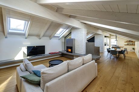 Airy, open-concept living space with exposed wooden beams, fireplace, and modern furnishings.