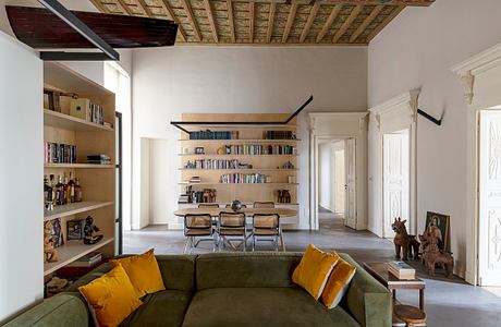 Ornate wood-beamed ceiling contrasts with modern furniture and shelving. Cozy living space.