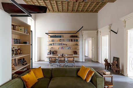 Ornate wood-beamed ceiling contrasts with modern furniture and shelving. Cozy living space.