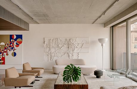 Spacious living room with concrete ceiling, neutral furniture, sculptural wall art, and potted plant.