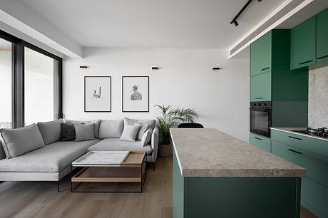 Modern, open-concept living space with minimalist furnishings, concrete countertops, and green cabinetry.