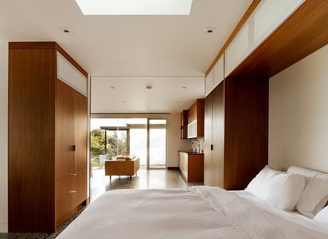 Spacious bedroom with wooden cabinetry, large window, and open-concept living area.