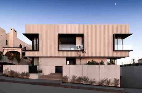 Modern building with pink paneled exterior, large windows, and tiered roofline.