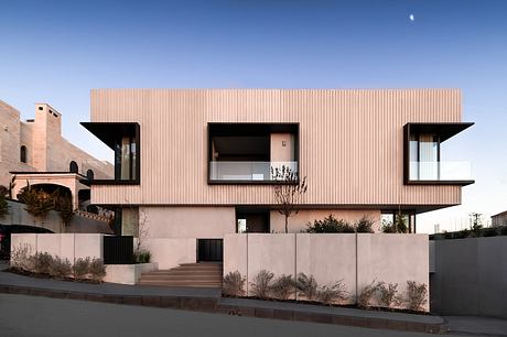 Modern building with pink paneled exterior, large windows, and tiered roofline.