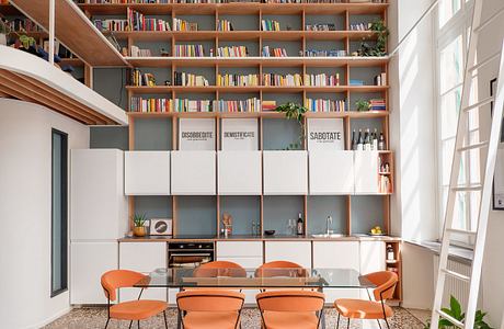 Cozy modern dining room with built-in bookshelves, orange chairs, and concrete floors.