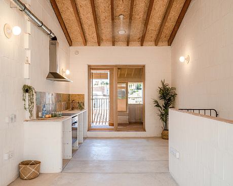 An airy, open-concept kitchen with rustic exposed wood beams and a sliding glass door leading to an outdoor space.