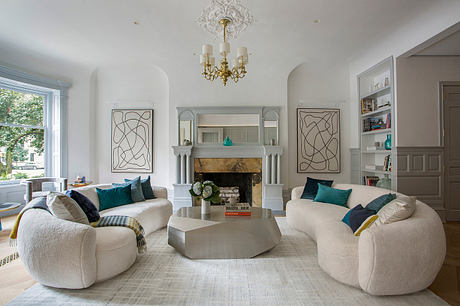 Elegant living room with ornate chandelier, built-in shelving, and abstract wall art.