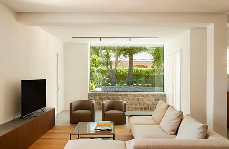 Bright, open living space with floor-to-ceiling window showcasing lush, outdoor garden.