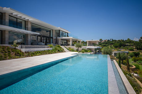 Luxury modern glass and concrete house with outdoor pool and lush landscaping.