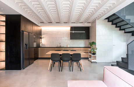 Sleek, modern kitchen with wood cabinets, black furnishings, and a vaulted white ceiling.