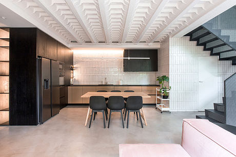 Sleek, modern kitchen with wood cabinets, black furnishings, and a vaulted white ceiling.