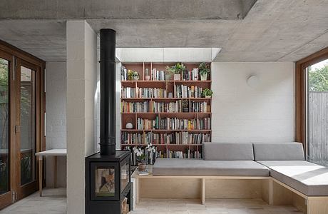 Cozy concrete and wood interior with built-in bookshelf, fireplace, and seating nook.