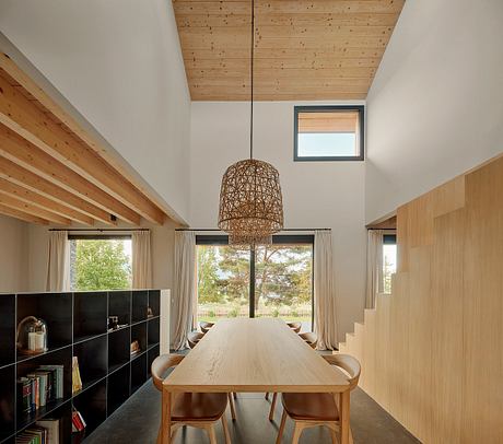 Spacious dining room with wooden beamed ceiling, large table, and woven pendant light.