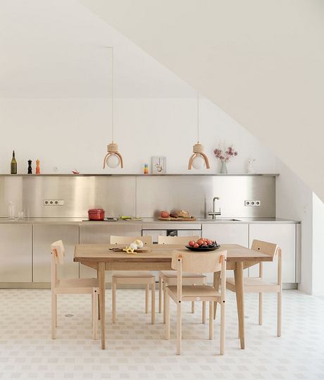 Minimalist kitchen design with wooden dining table and chairs, pendant lighting.