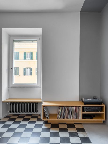 Minimalist room with checkered floor, wooden media cabinet, and large window framing exterior.