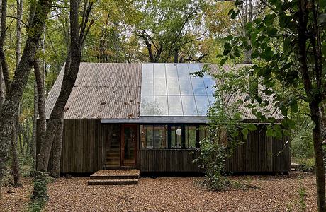 A rustic wooden cabin nestled in a lush forest, with a modern glass facade reflecting the surrounding greenery.