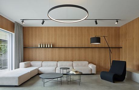 Minimalist living room with wooden walls, circular lighting fixture, and modern furniture.