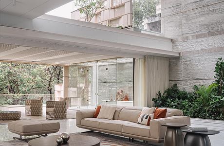 Sleek, modern living room with glass walls, stone accents, and a stylish rug.