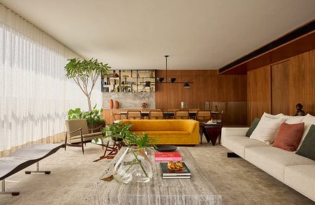 A modern, cozy living room with warm wooden paneling, a yellow sofa, and potted plants.