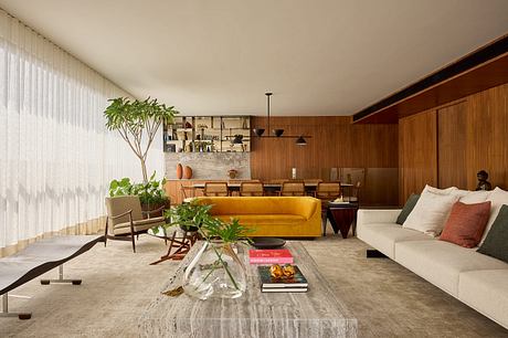 A modern, cozy living room with warm wooden paneling, a yellow sofa, and potted plants.