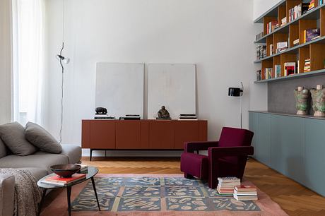 Modern living room with built-in shelving, burgundy armchair, and patterned area rug.