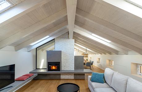 Bright, airy attic space with vaulted wooden ceiling, fireplace, and open floor plan.