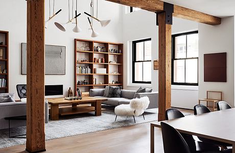 Cozy modern loft with exposed wooden beams, built-in shelves, and a plush sectional sofa.