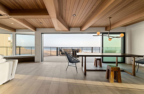 Spacious open-concept living area with high ceilings, wood beams, and panoramic ocean views.