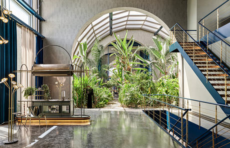 Striking architectural features include the arched windows, lush greenery, and modern steel staircases.