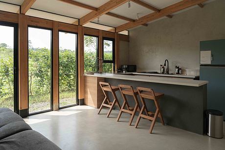 Spacious kitchen with floor-to-ceiling windows, wooden beams, and minimalist furnishings.