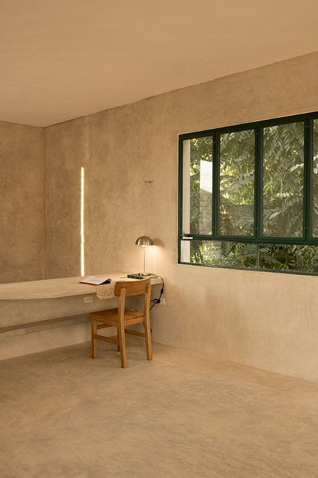 Minimalist home office with large windows overlooking lush greenery outside.