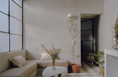 Minimalist living room with neutral color scheme, geometric tiled floor, and natural elements.