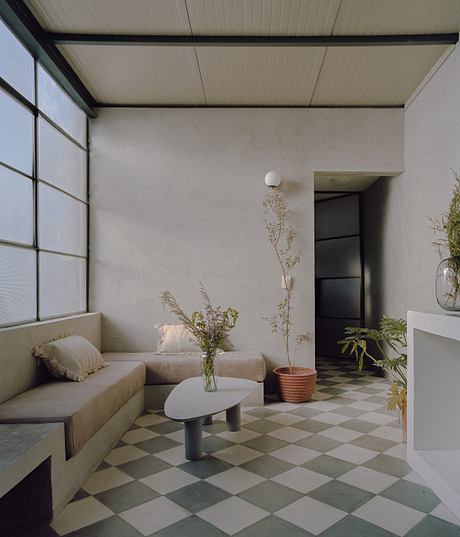 Minimalist living room with neutral color scheme, geometric tiled floor, and natural elements.