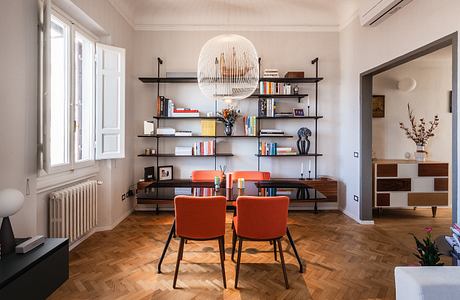 A modern and stylish living space with a statement pendant light, open shelving, and vibrant accents.