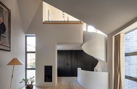 Spacious modern living room with high ceilings, exposed beams, and a stone fireplace.