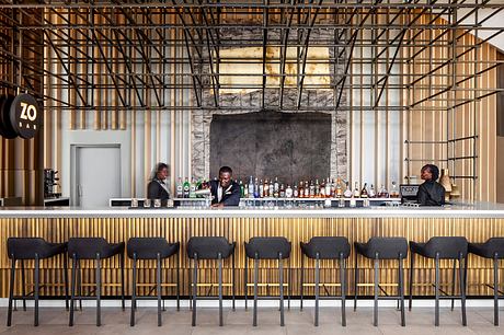 A modern, open-concept bar with a steel-framed facade, wooden accents, and an impressive bar counter.
