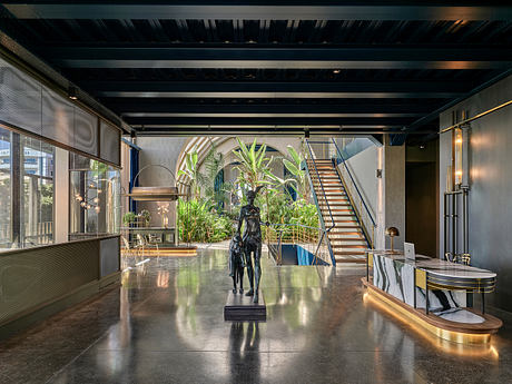 Striking industrial-style interior with lush greenery, sculptural elements, and sleek metallic accents.
