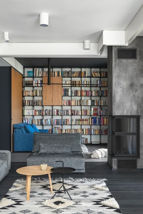 Modern and cozy living room with extensive built-in bookshelves, gray furniture, and wooden accents.