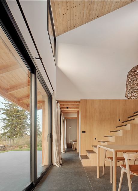 Modern, minimalist interior with wood paneling, large windows, and a sleek staircase.