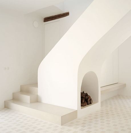 Modern, minimalist interior design with arched niche, steps, and tiled floor.