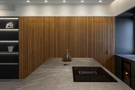 Sleek, modern kitchen with wooden paneling, marble countertops, and recessed lighting.