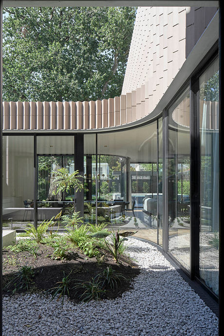 A modern architectural design featuring a glass-enclosed courtyard with lush vegetation.