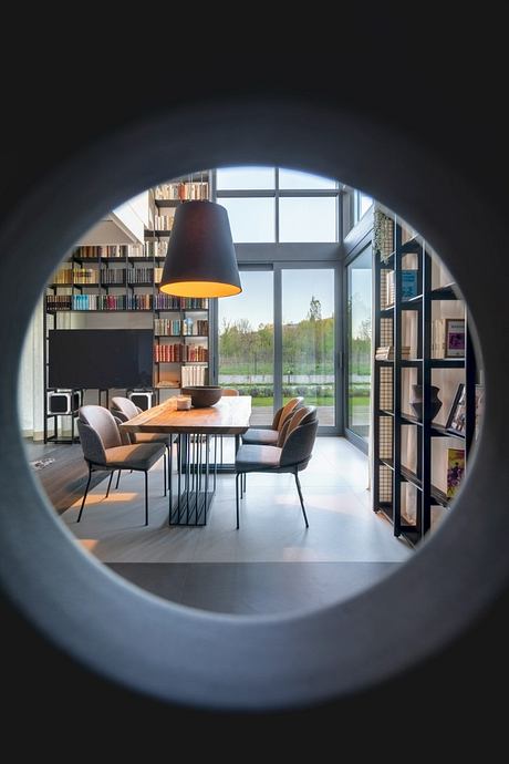 Spacious modern dining area with wooden table, chairs, and large window overlooking nature.