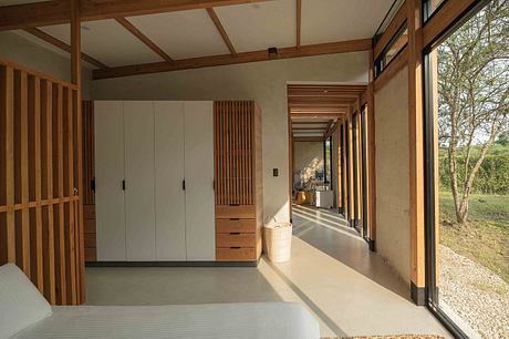 A modern, wooden-framed interior with minimalist furnishings and expansive windows overlooking nature.